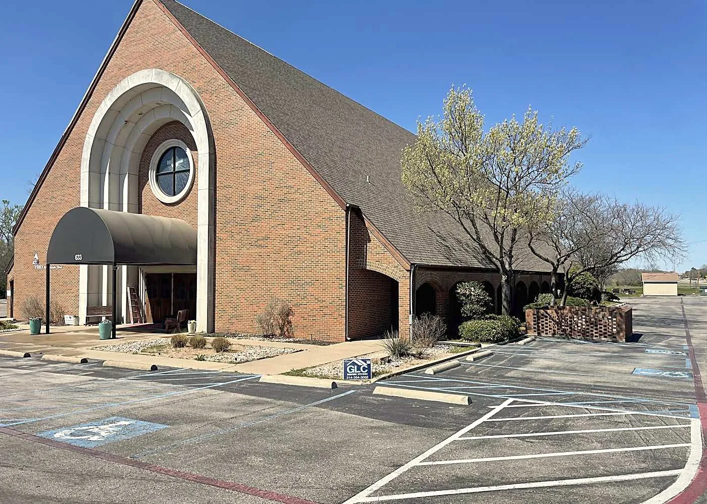 A brick church with a steep A-frame shingle roof