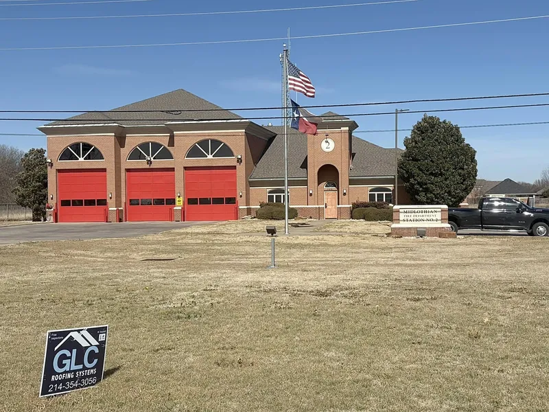 Midlothian Fire Station No. 2, a brick station with three red bay doors, with the GLC sign on the lawn