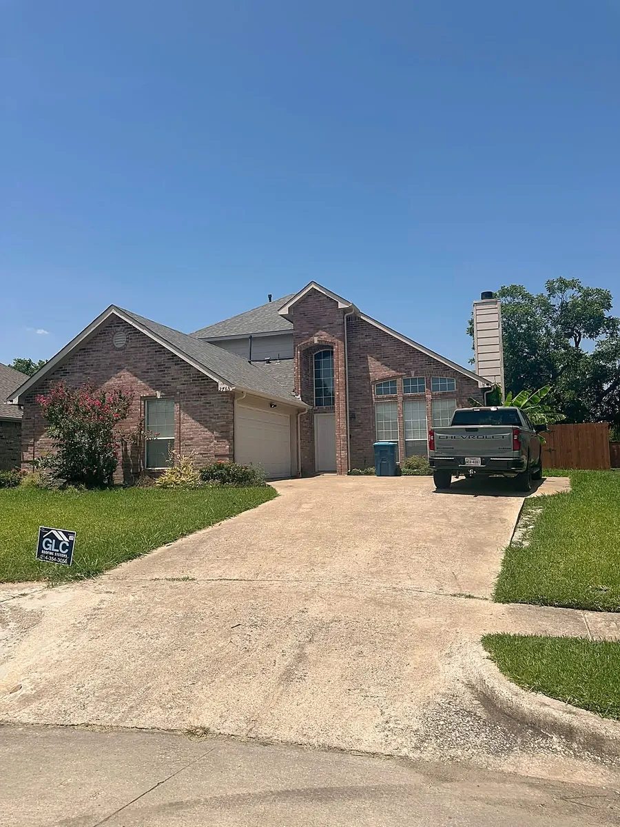 A brick two-story home in Rockwall with a new roof and gutters and the GLC sign in the yard